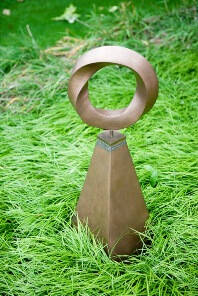 Metal pyramid shaped sculpture with a ring shape at the top.